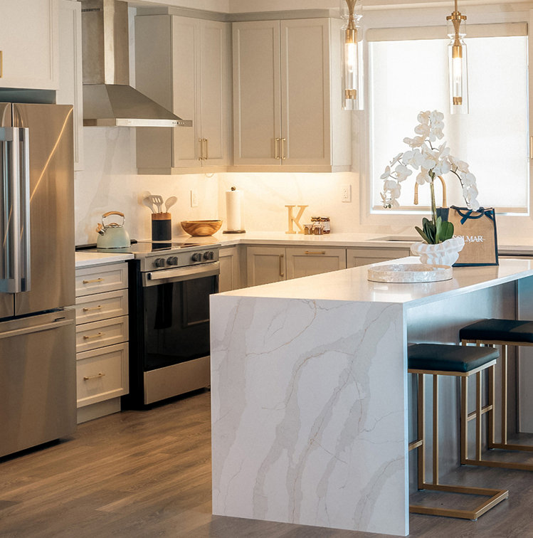 Bright kitchen with marble island, cream cabinetry and gold hardware